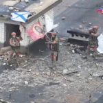 Russian service members wave flags on the roof of a building in Velyka Novosilka